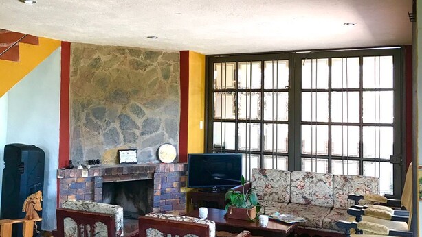Una sala de estar con chimenea de piedra, televisión y sofá.