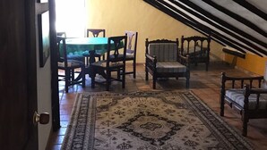 Habitación en el ático con una mesa de comedor, sillas y un tapete estampado.