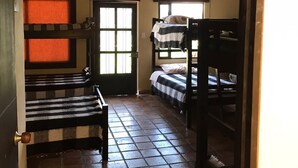 Una habitación con dos literas, una puerta con ventanal y piso de baldosas.