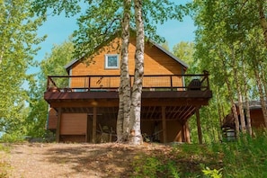 A wooden cabin with a balcony, surrounded by trees.