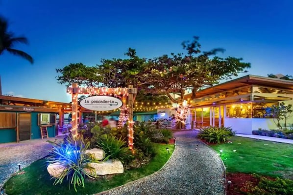 A well-lit outdoor area with a sign for 'la pescadería' and a pathway leading to a building.