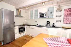 Une cuisine moderne avec des meubles blancs, des appareils en acier inoxydable et une table à manger en bois.