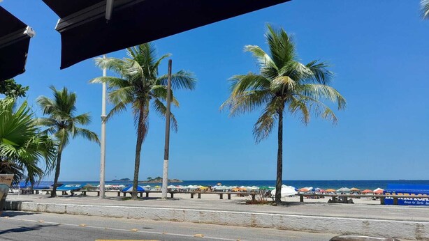 Blick auf einen Strand mit Palmen, einem klaren Himmel und einer Straße mit Fußgängerüberweg.