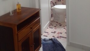 Ein Badezimmer mit Toilette, Waschbecken und Spiegel. Auf dem Boden liegt ein blaues Handtuch.
