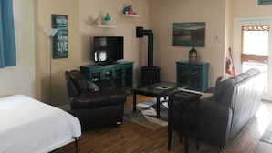 A living room with a sofa, a television, a fireplace, and a ceiling fan. - Hepworth Studio Apartment, 3 Wooded Acres (Hepworth)
