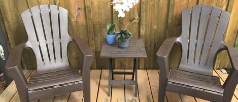 Two Adirondack chairs with a small table and a potted plant between them.