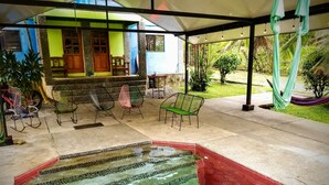 A covered outdoor area with a swimming pool, chairs, and a hammock. - Beach house with a pool (Pavones)