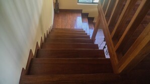 A wooden staircase with a handrail, leading to a landing with a window and a bottle on a shelf. - Beach house with a pool (Pavones)