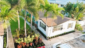 A residential property with a small house, surrounded by palm trees and a well-maintained lawn. - POMPANO BEACH DELIGHT RETREAT 5' BEACH (Pompano Beach)