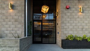 Une entrée d’immeuble avec une porte en verre, le numéro « 516 » sur la porte et deux lampes fixées au mur.