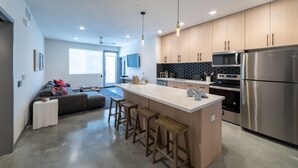 Une cuisine moderne dotée d’un îlot central, d’appareils électroménagers en acier inoxydable et d’armoires en bois.