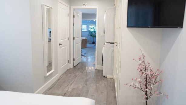 A hallway with white doors, a mounted flat-screen TV, and a wooden floor. - 1BR *HOUSE* in GLENDALE with PRIVATE FENCED YARD (p55) (Glendale)