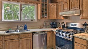 A kitchen with wooden cabinets, a stainless steel dishwasher, a stove, and a window with a view of trees. - 8 Mi to Dtwn Achorage! Home w/ Pet-Friendly Yard (Anchorage)