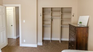 A bedroom with a walk-in closet, a dresser, and a bed.