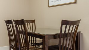 A dining area with a table and four wooden chairs. A framed quote is on the wall.
