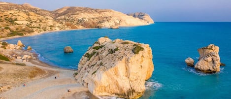 A coastal landscape with rocky formations and a beach.