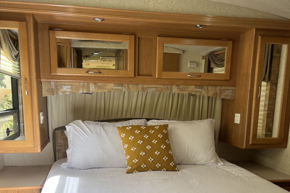 A bedroom with a large bed, wooden headboard, and built-in cabinets.