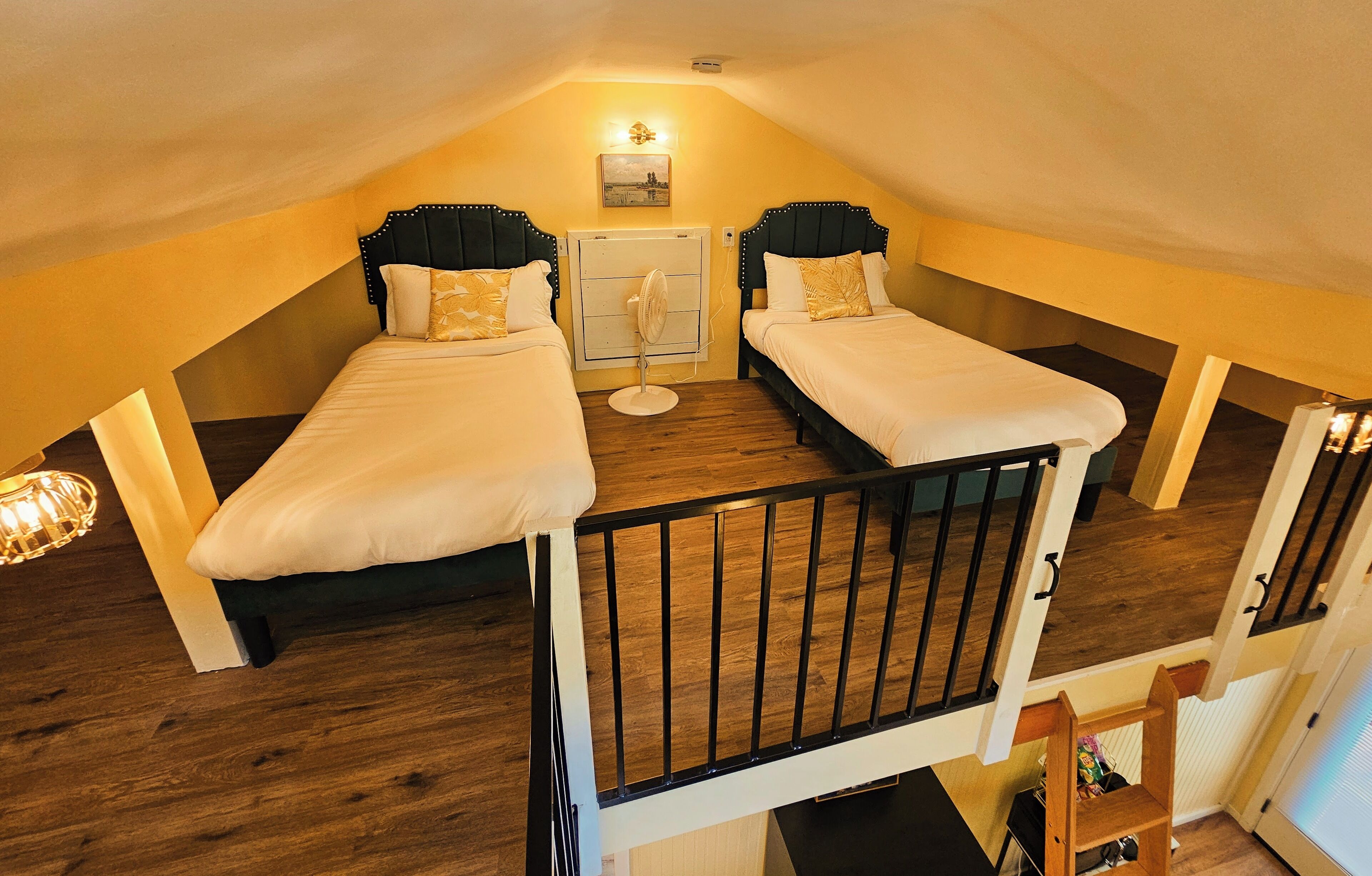 A room with two beds, a ceiling fan, and a small table.
