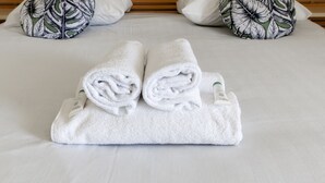 A neatly made bed with two rolled white towels and a tube of cream. - Appartement Conquistar - Welkeys (Cabourg)