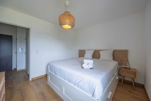 A bedroom with a bed, bedside table, and a hanging light fixture. - Appartement Conquistar - Welkeys (Cabourg)