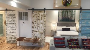 Ein Schlafzimmer mit einem Bett, einem grauen Sofa und einer Holzbank.