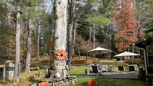 A rustic outdoor seating area with a fire pit, chairs, and umbrellas.