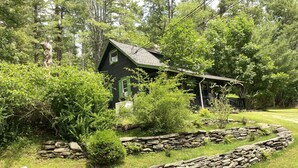 A rustic cabin surrounded by lush greenery and stone walls.