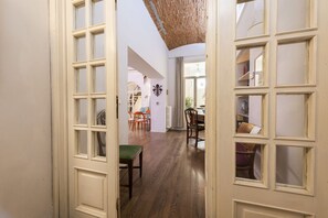 Un pasillo con piso de madera, paredes blancas y una puerta de hojas múltiples.