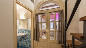 Ein Zimmer mit Holzboden, einem weißen Waschbecken, einer gefliesten Rückwand und einer Tür mit Fenster.