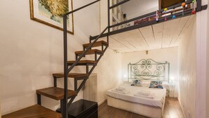 Ein Schlafzimmer mit einem Bett, einer Holztreppe, einem Heizkörper und einem Wandregal.