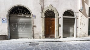 A building with three arched doorways, one of which is open, revealing a wooden door.