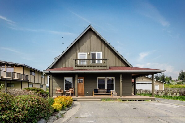 A two-story house with a front porch, a garage, and a small garden area. - The Atlas - Sauna and Beach Access (Dr)