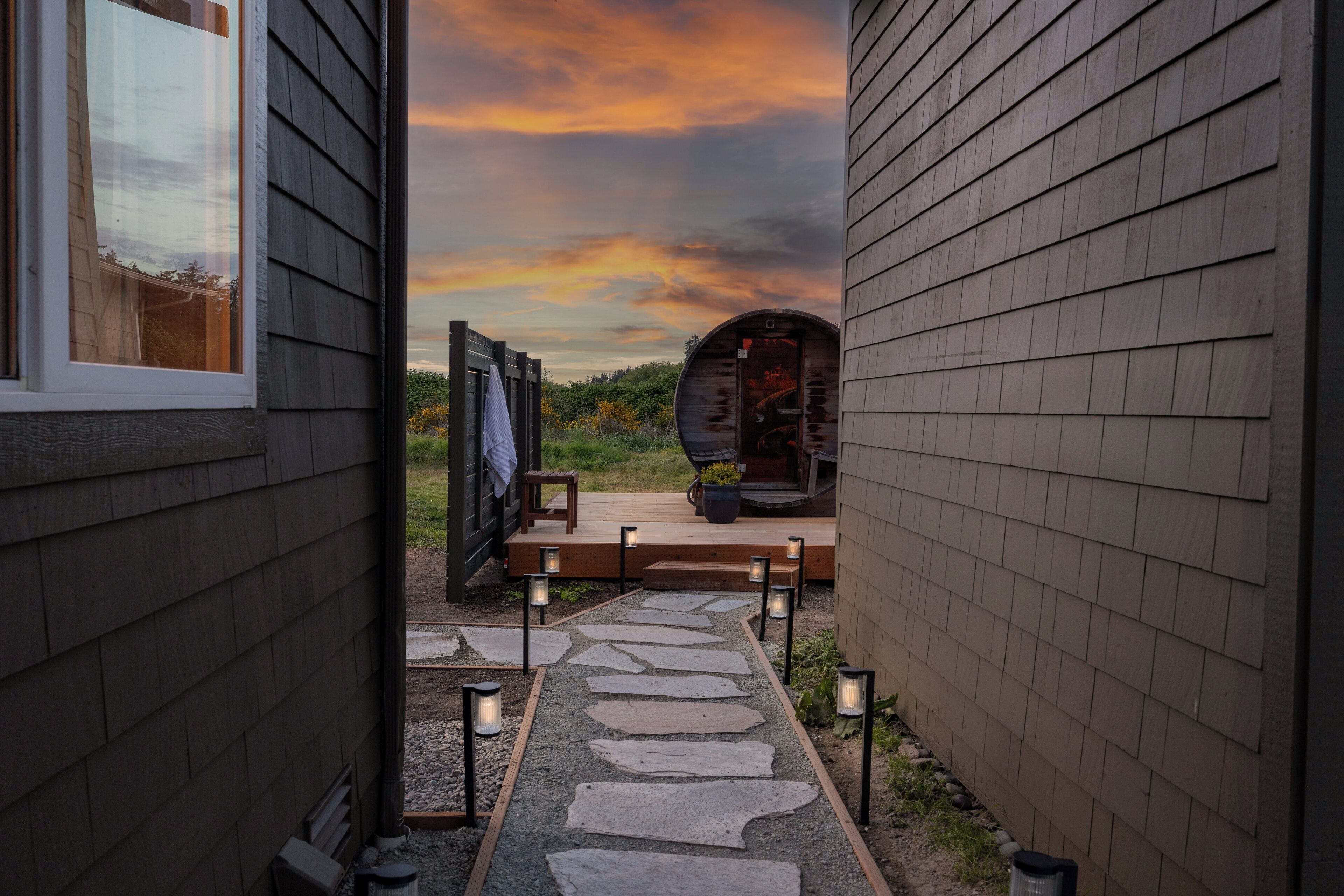 A stone pathway leading to a wooden deck with a view of a sunset.