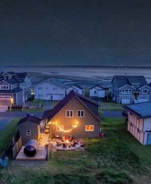 Un quartier résidentiel avec des maisons, une pelouse et un espace barbecue agrémenté de guirlandes lumineuses.