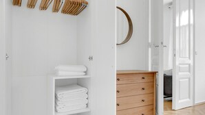 Un bagno bianco con un armadietto in legno, un portascopino e un comò in legno con cassetti.
