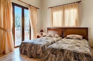 Two single beds with patterned bedspreads, a wooden headboard, and a nightstand with a lamp.