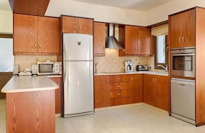 Enjoy cooking in this well-equipped kitchen with a central island, stainless steel appliances, and a large window offering a view of the outdoors.