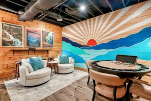 Quarto com parede de madeira, um mural, dois sofás brancos, uma mesa redonda e um laptop.