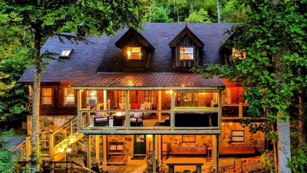 Une cabane dotée d’un balcon au deuxième étage, de fondations en pierre et d’une terrasse en bois.