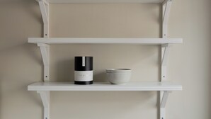 Une étagère blanche sur laquelle sont posés un chandelier et un bol.