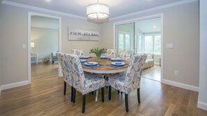 A dining area with a round table, patterned chairs, and a chandelier.