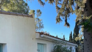 A courtyard with a tiled floor, a white building with a green door, and a small table. - Family Cottage With Pool and Spectacular Views in a Rural Setting (Velez-Malaga)