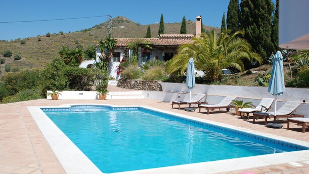 A swimming pool with lounge chairs and umbrellas, surrounded by greenery and a hillside in the background. - Family Cottage With Pool and Spectacular Views in a Rural Setting (Velez-Malaga)