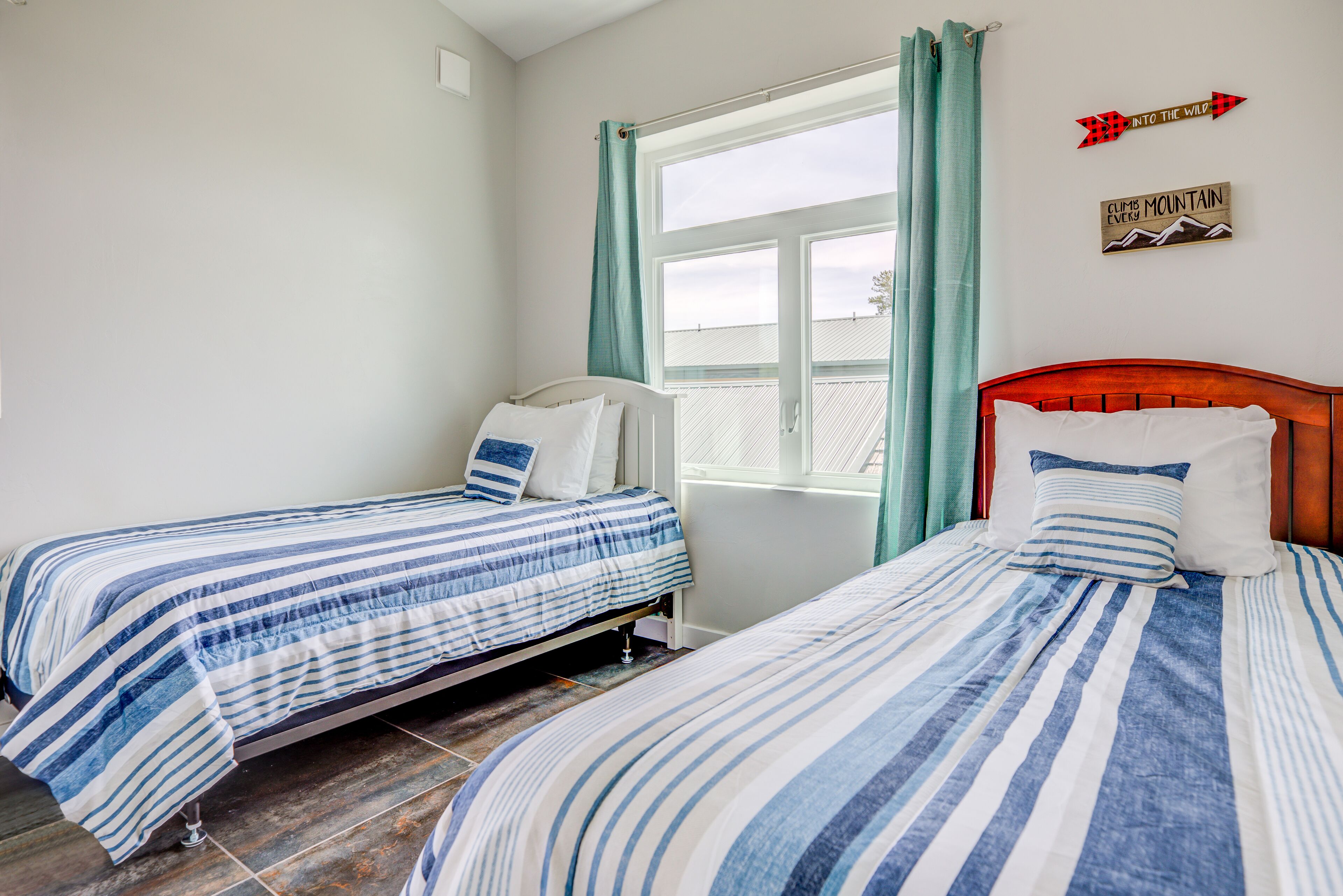 Une chambre avec deux lits simples, une fenêtre avec des rideaux et des éléments décoratifs sur les murs.