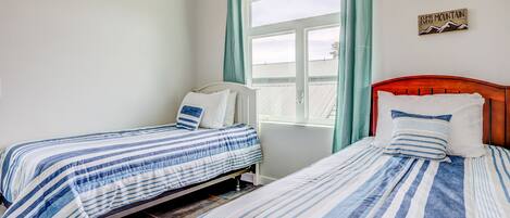 Une chambre avec deux lits simples, une fenêtre avec des rideaux et des éléments décoratifs sur les murs.