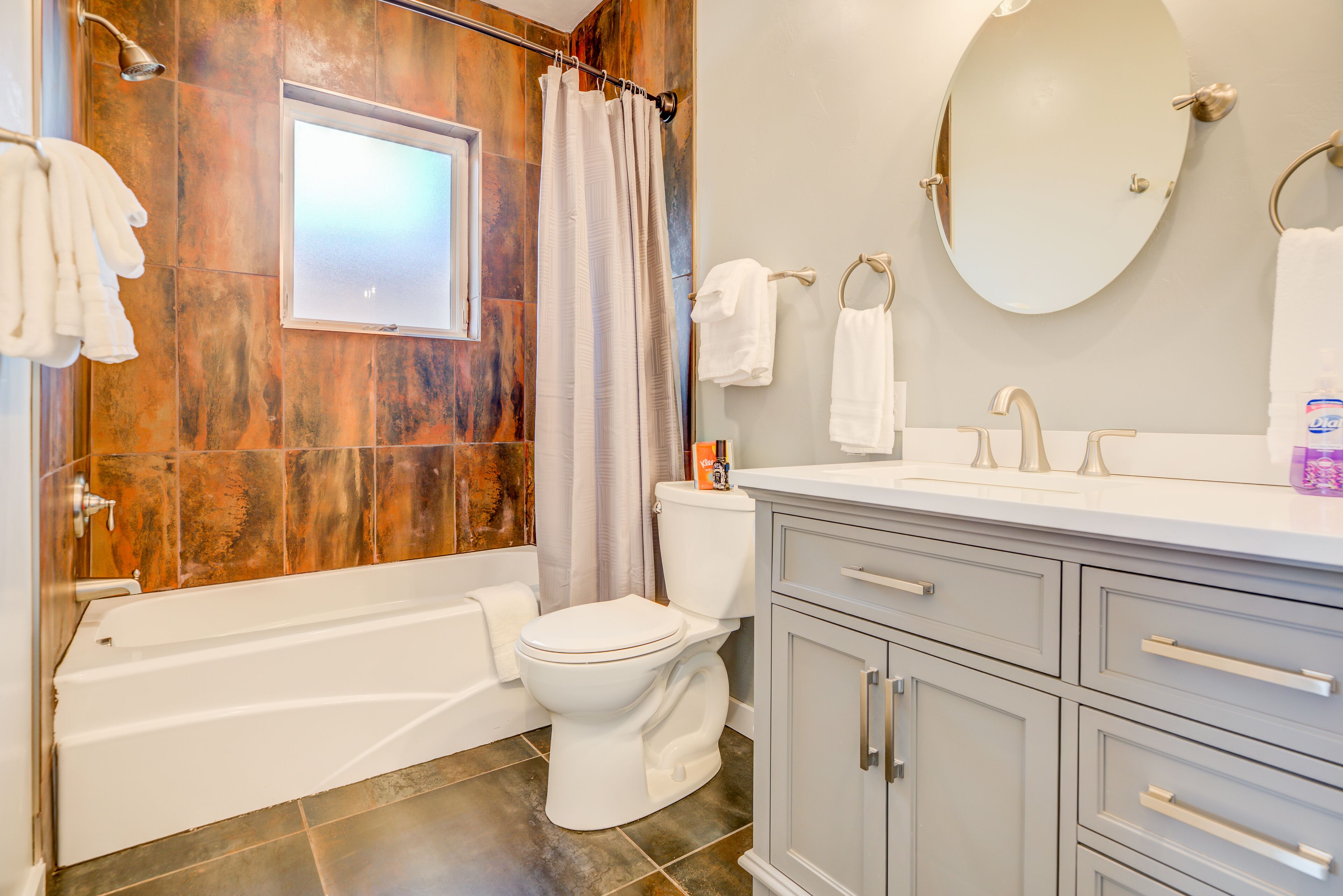 A bathroom with a bathtub, toilet, and vanity with drawers.