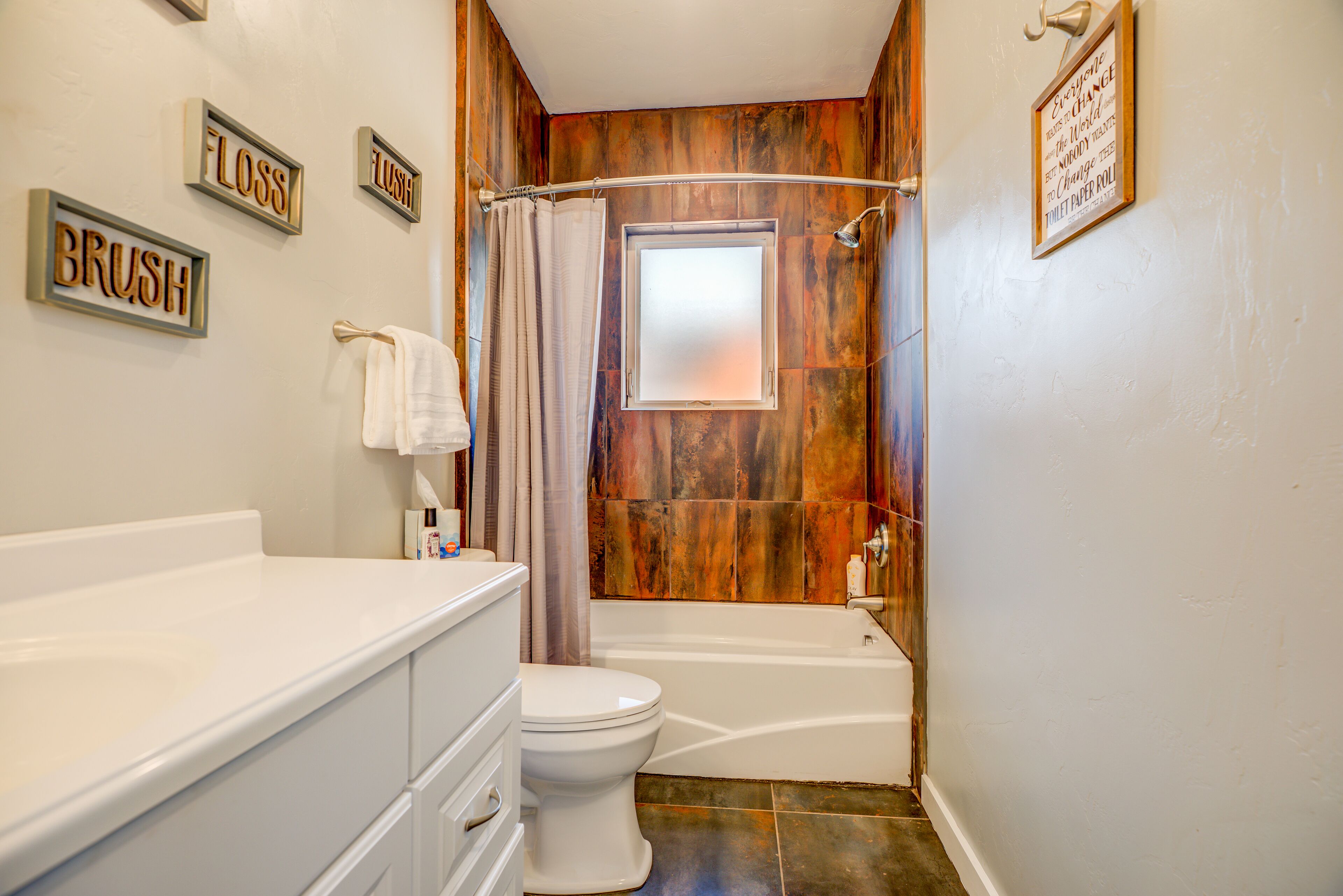 A bathroom with a wooden wall, a white bathtub, a white toilet, and a vanity with drawers.