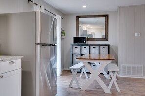 A compact kitchen with a stainless steel refrigerator, a microwave, and a wooden table with a bench. - Charming modern duplex minutes to downtown Fayetteville (Fayetteville)