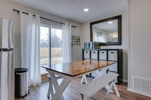 Een keuken met een houten tafel, een witte bank en een magnetron.