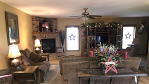 Een gezellige woonkamer met een open haard, een plafondventilator en een kerstboom.